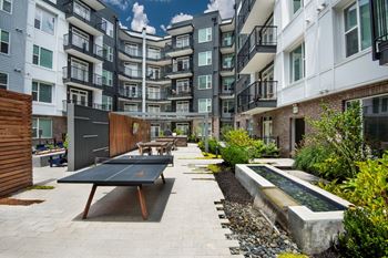 furnished courtyard with ping pong table and benches in front of an apartment building